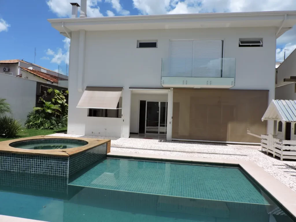 Área externa residencial com piscina, spa integrado e piso em tons claros